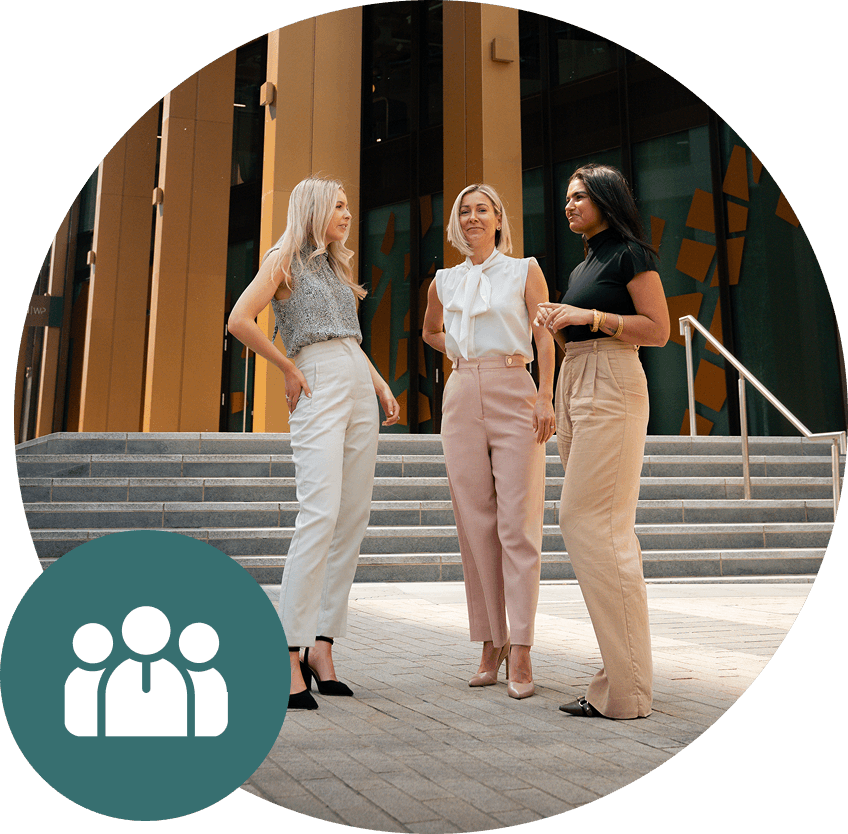 Three women in business attire conversing outside a modern building.