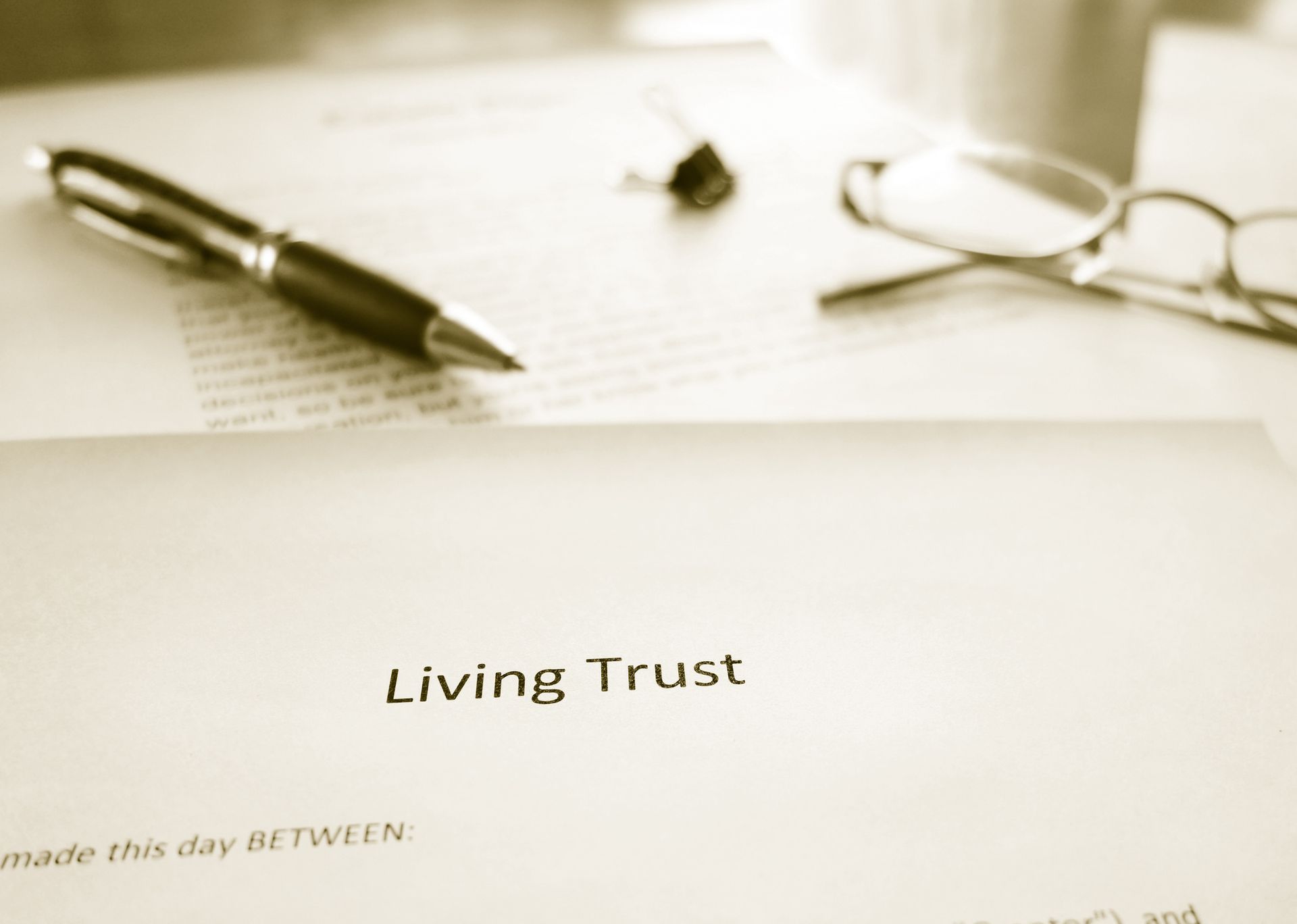 Living Trust document with pen, glasses, and stapler on a desk.
