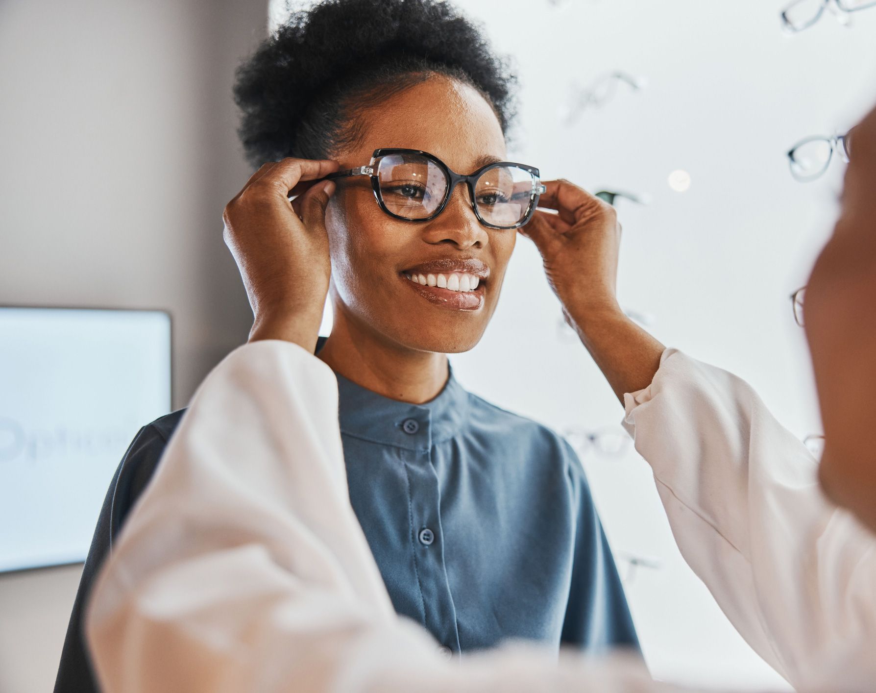 Woman trying on eyeglasses with assistance from an optician.