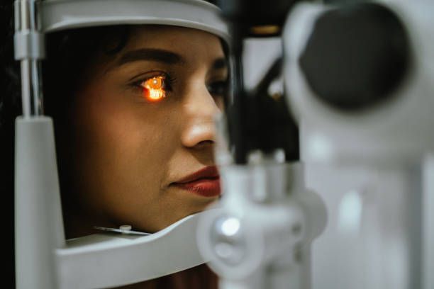 Woman getting an eye exam at an ophthalmologist's office; the doctor is examining her eye with a slit lamp.