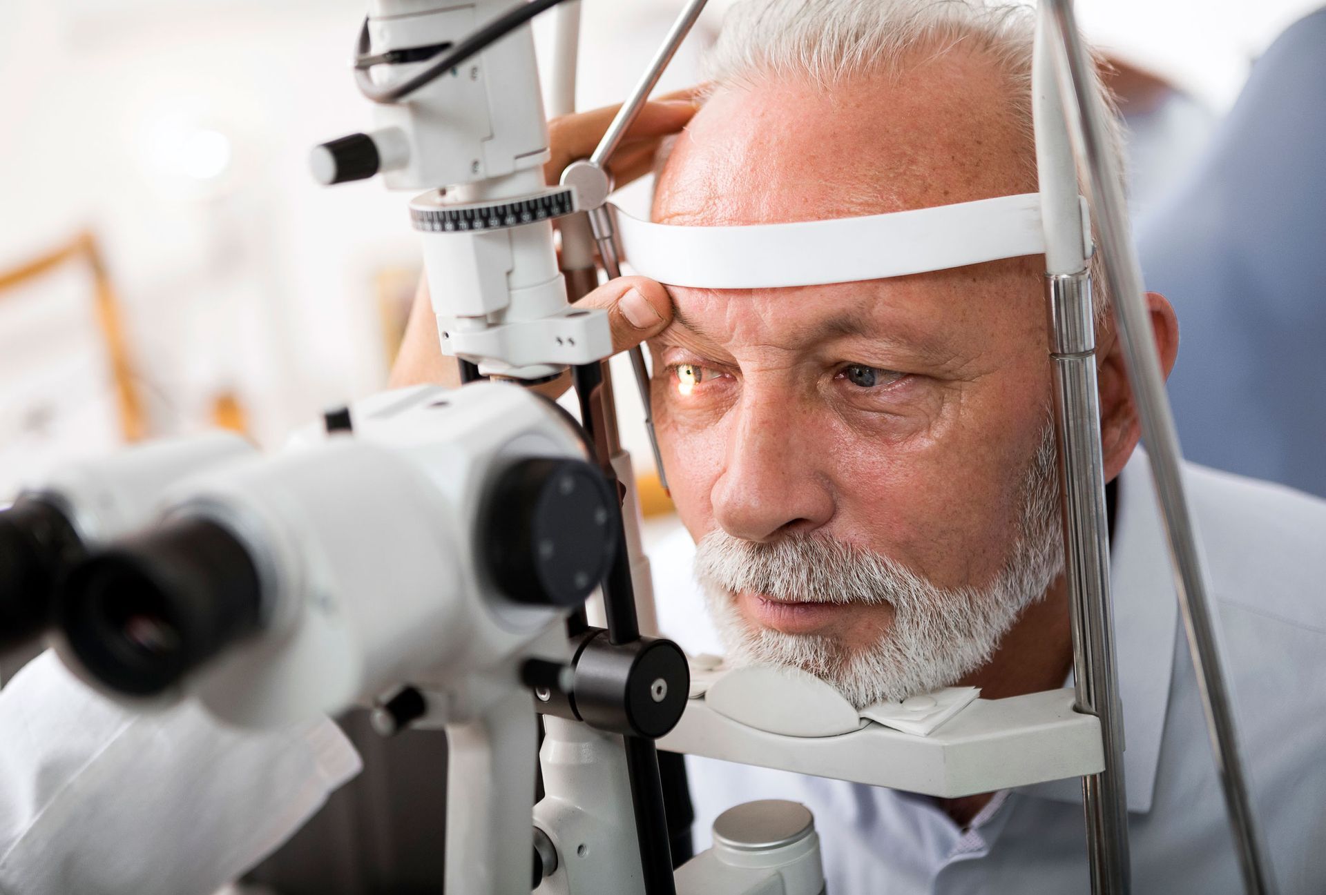 Man getting an eye exam using a slit lamp, examining his eye in a doctor's office.