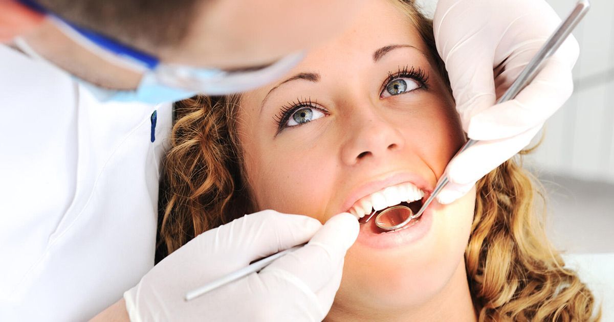 A woman is getting her teeth examined by a dentist.