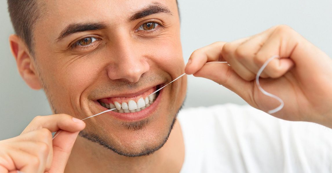 a man is flossing his teeth with a dental floss .