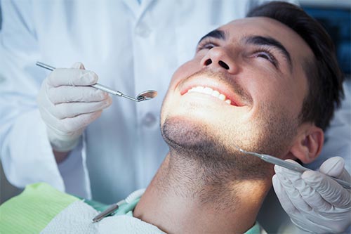 a man is having his teeth examined by a dentist .