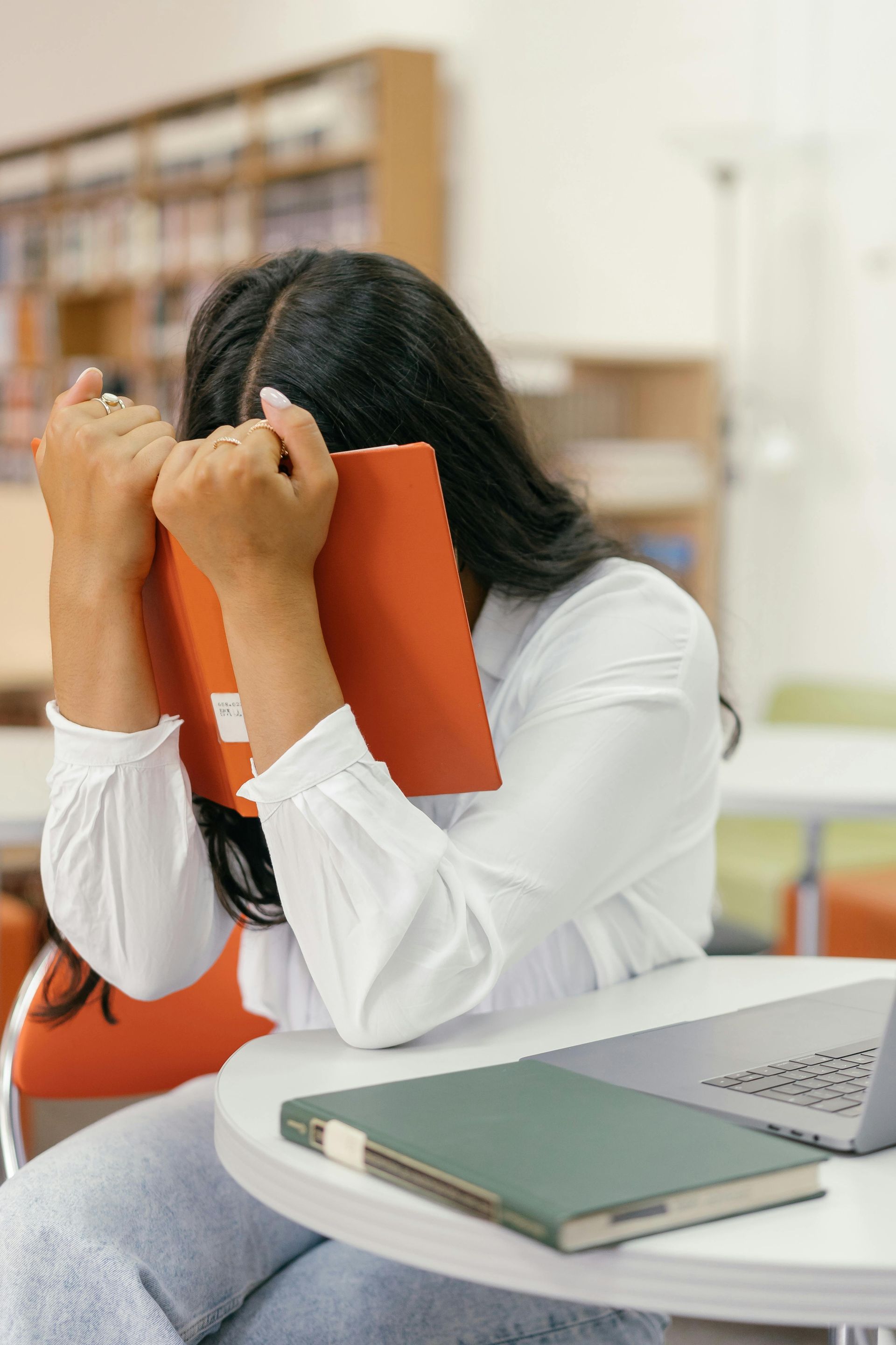 A woman hides her face behind a library book