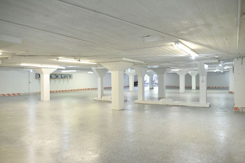 Empty, bright white storage space with numerous support pillars and fluorescent lighting.