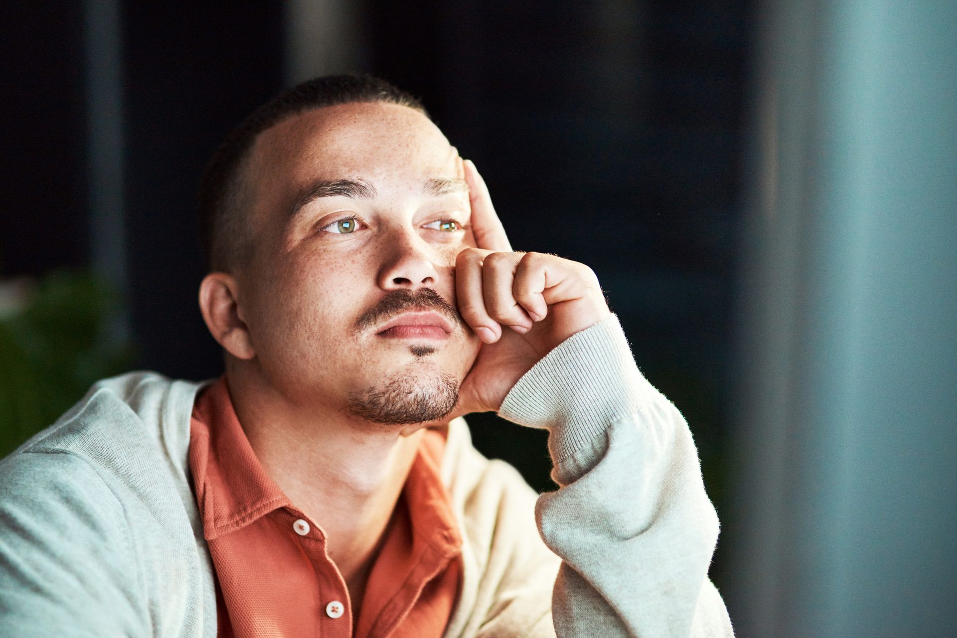 Young adult looking thoughtfully out a window in a therapy office near Syracuse NY, working with the