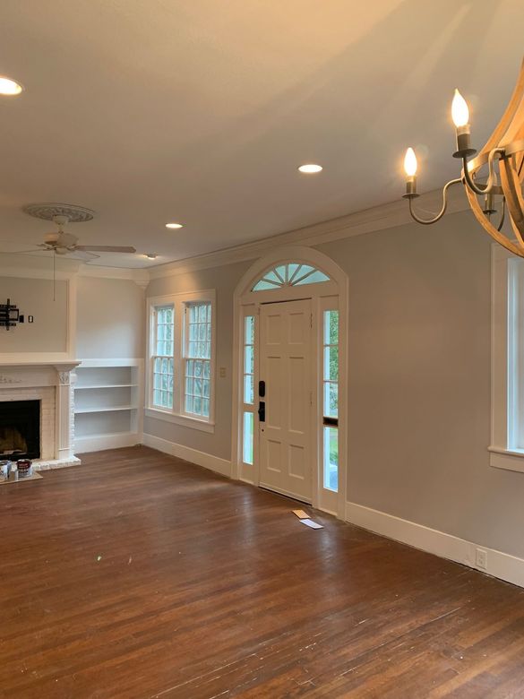 An empty living room with hardwood floors , a fireplace , and a chandelier.