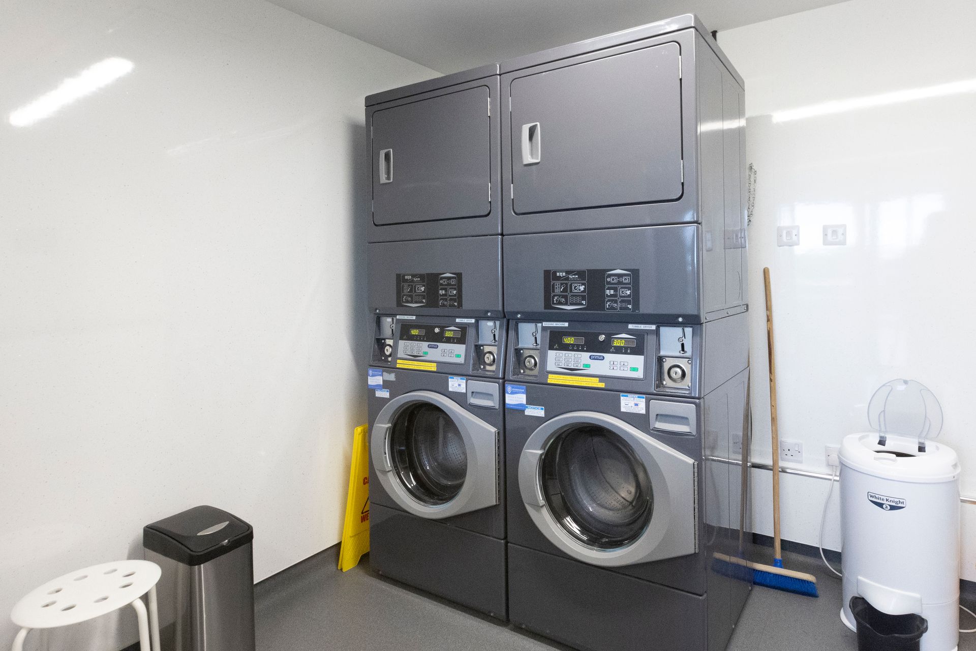 A laundry room with two washers and dryers stacked on top of each other.
