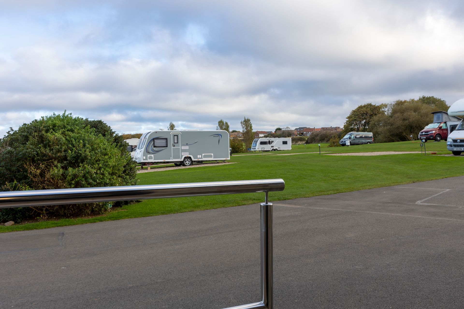 A row of camper vans are parked in a grassy field