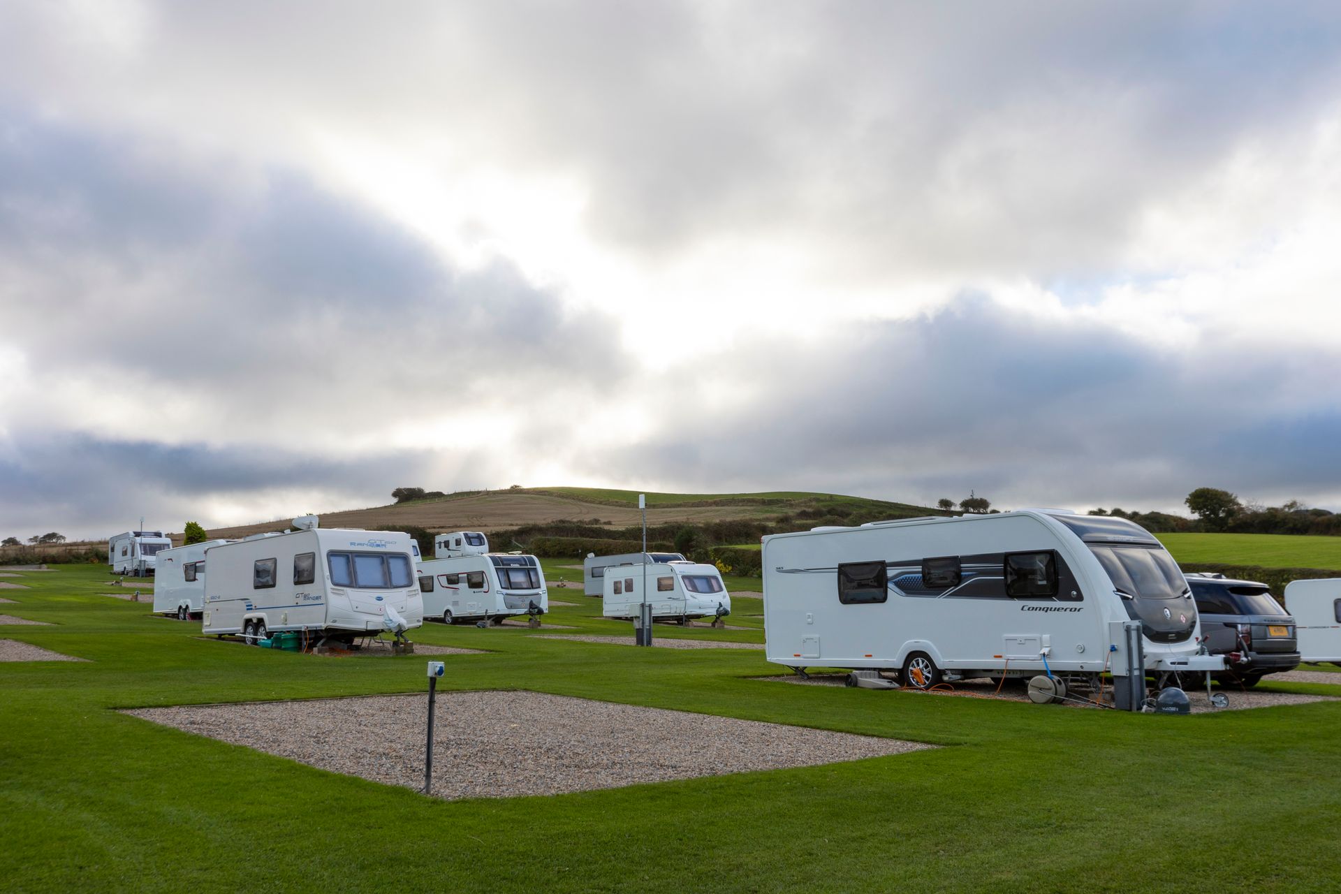 A row of white caravans parked in a grassy field