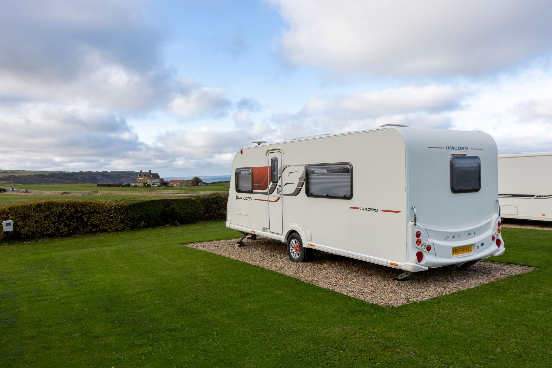 A white caravan is parked in a grassy field.