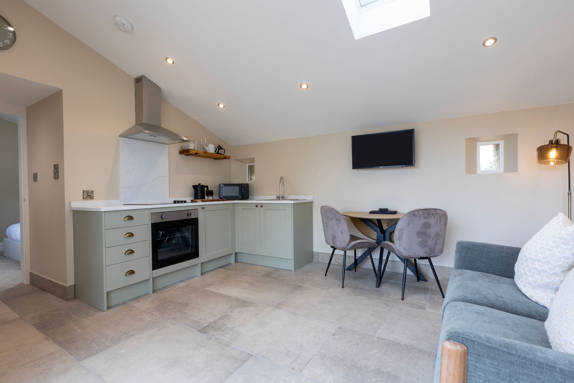A living room with a couch , table , chairs and a kitchen.