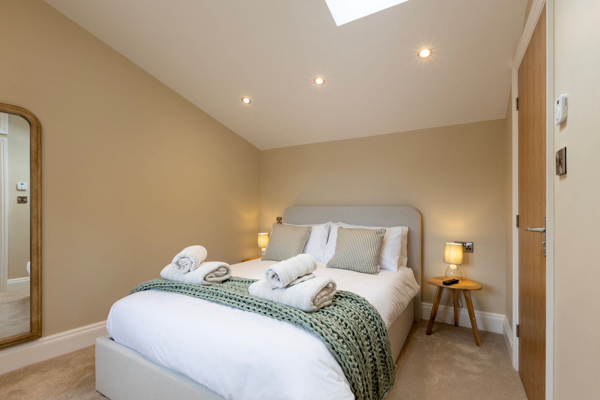 A bedroom with a large bed and a mirror.