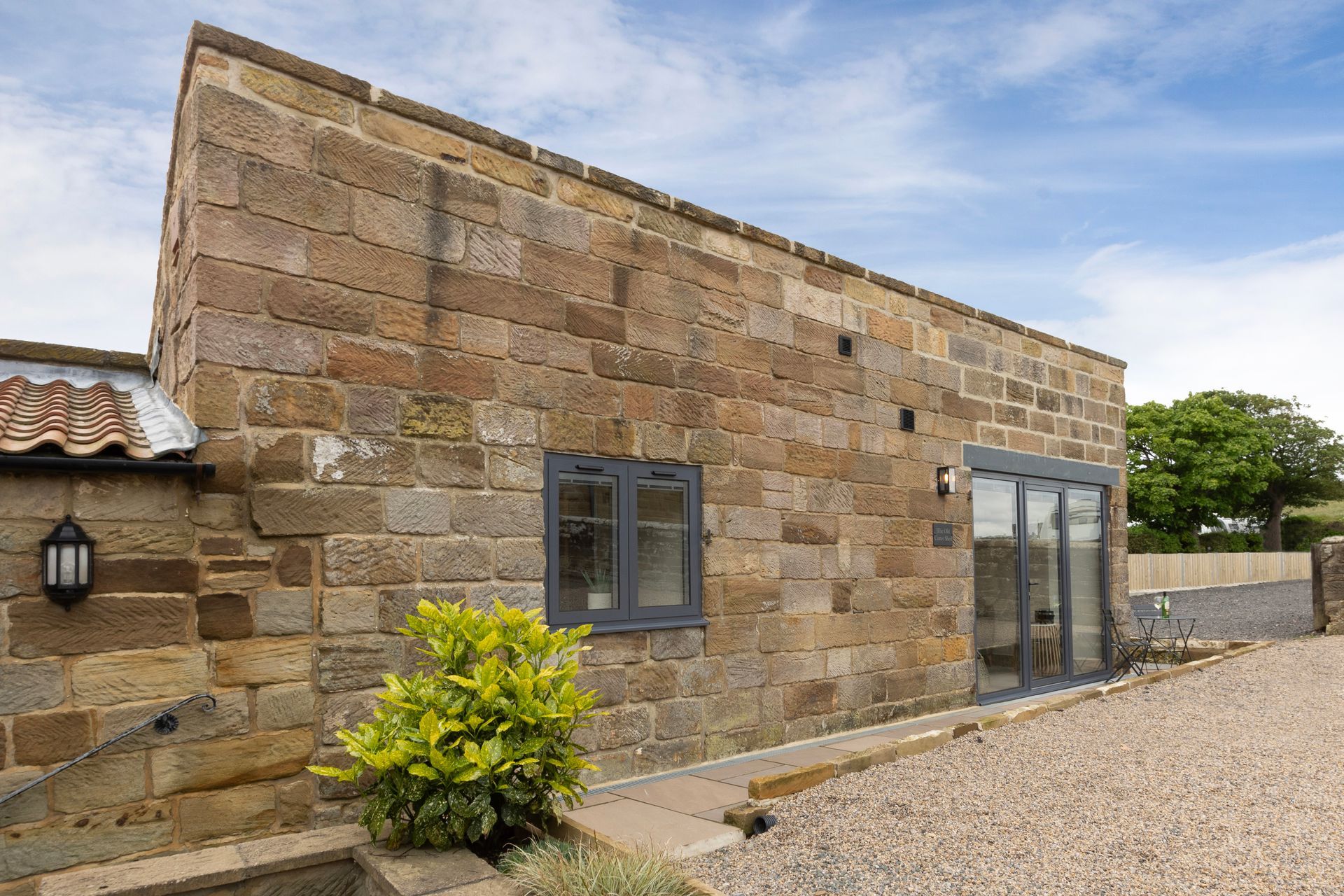 A large stone building with a lot of windows and a gravel driveway in front of it.