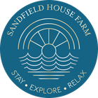 The logo for sandfield house farm caravan park in whitby is a blue circle with a sun and waves in it.
