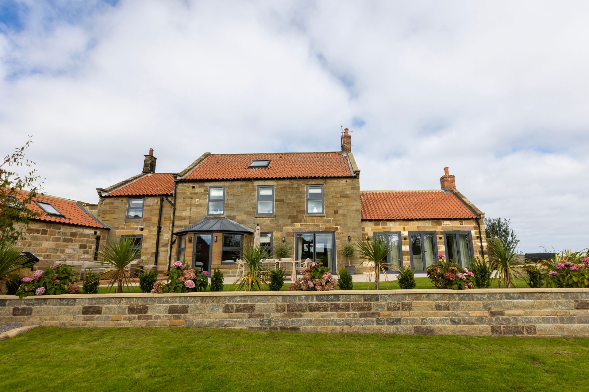 A large stone house with a brick wall in front of it.