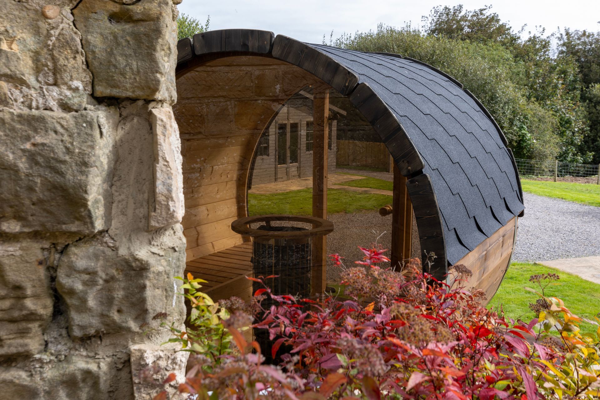 A wooden barrel is sitting next to a stone wall.