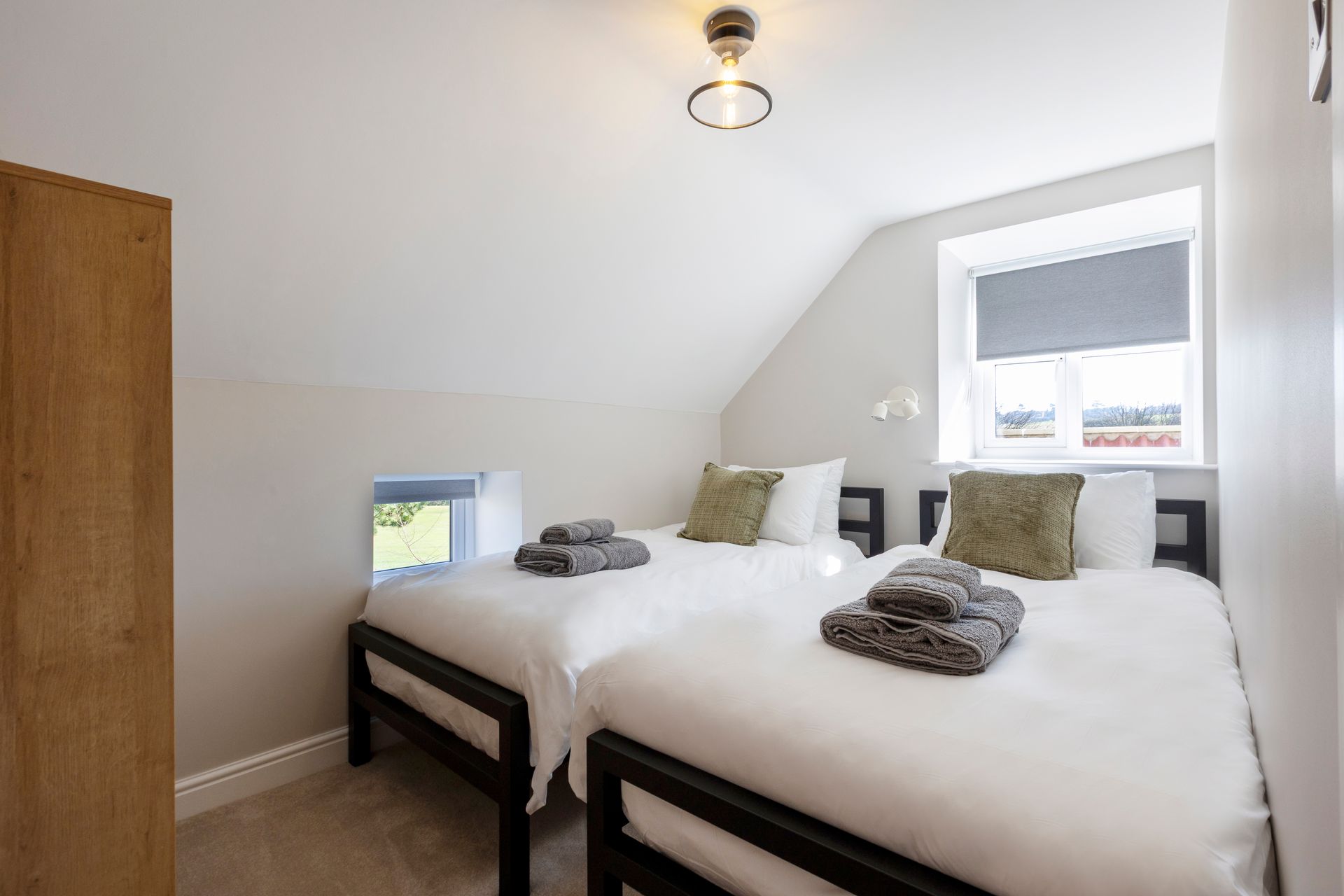 A bedroom with two beds and a window.