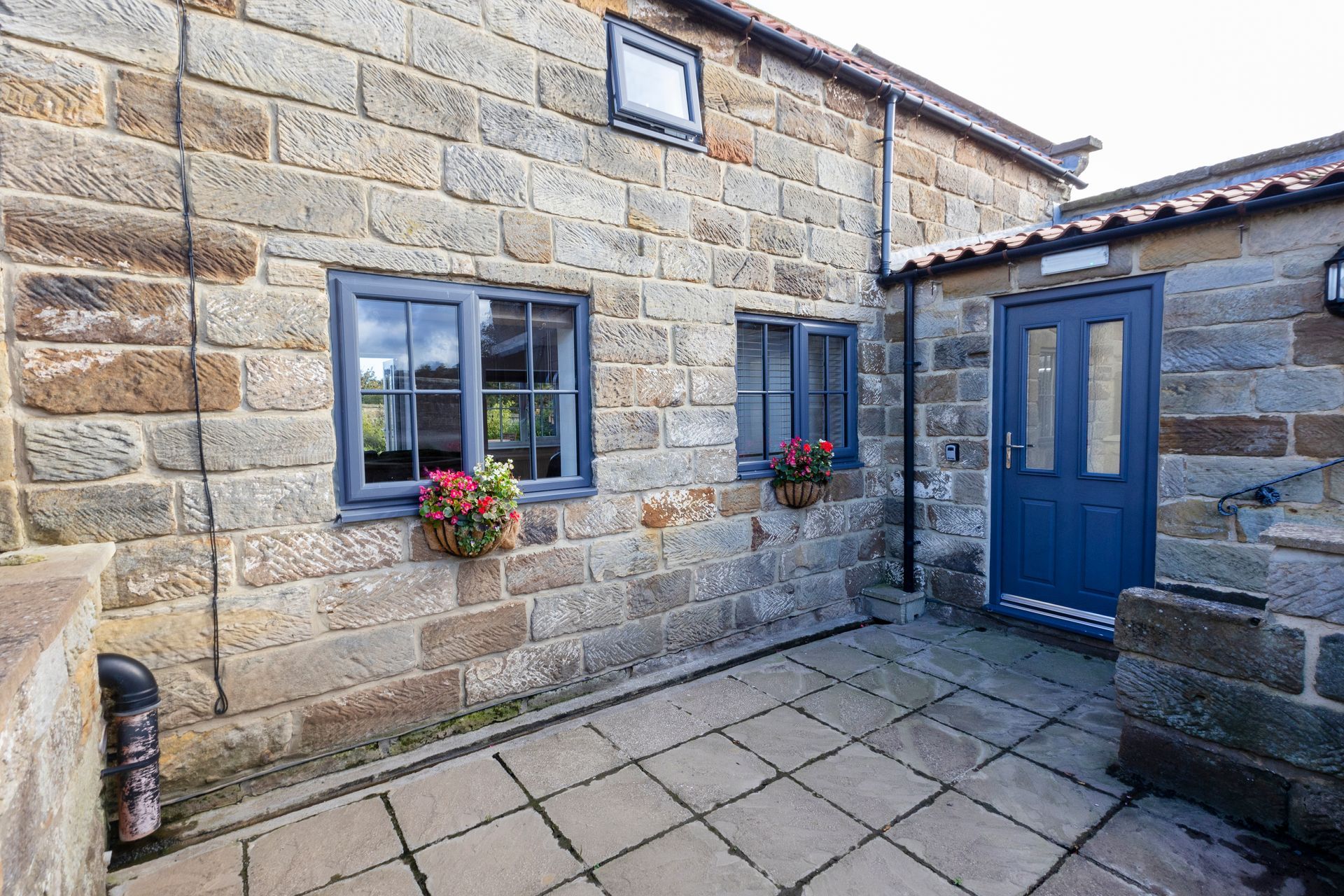 A stone building with a blue door and two windows.