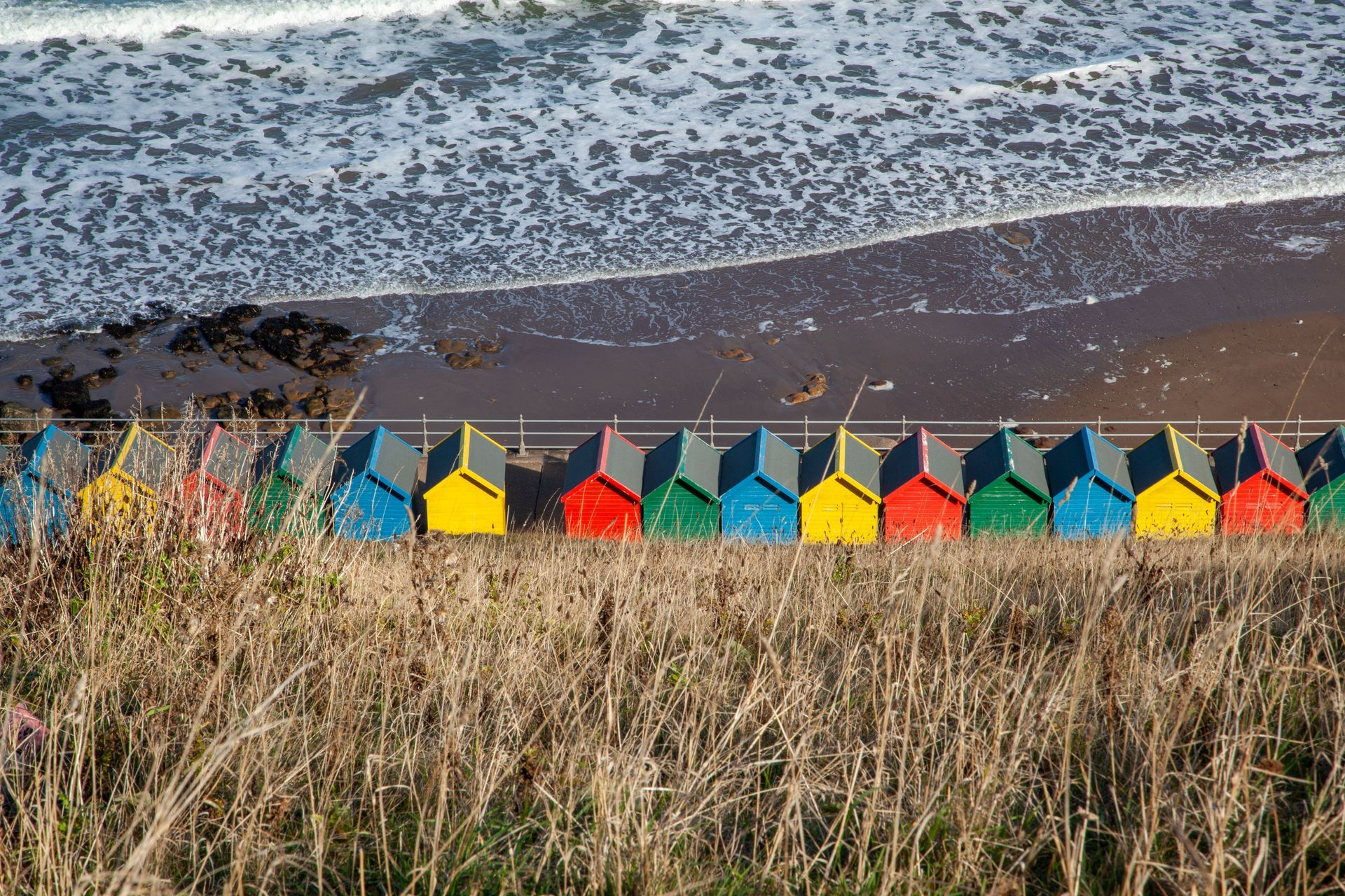 A row of colorful beach huts next to the ocean
