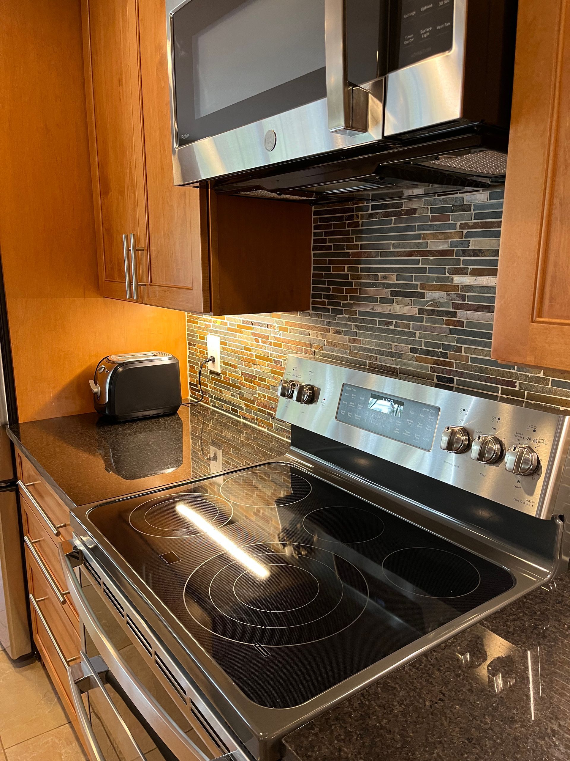 Kitchen with dark countertops, stainless steel appliances, and a mosaic tile backsplash.