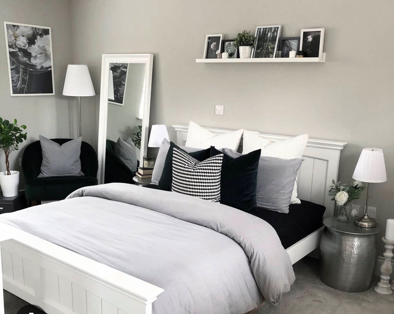 A bedroom with a bed , a chair , a mirror and a shelf.