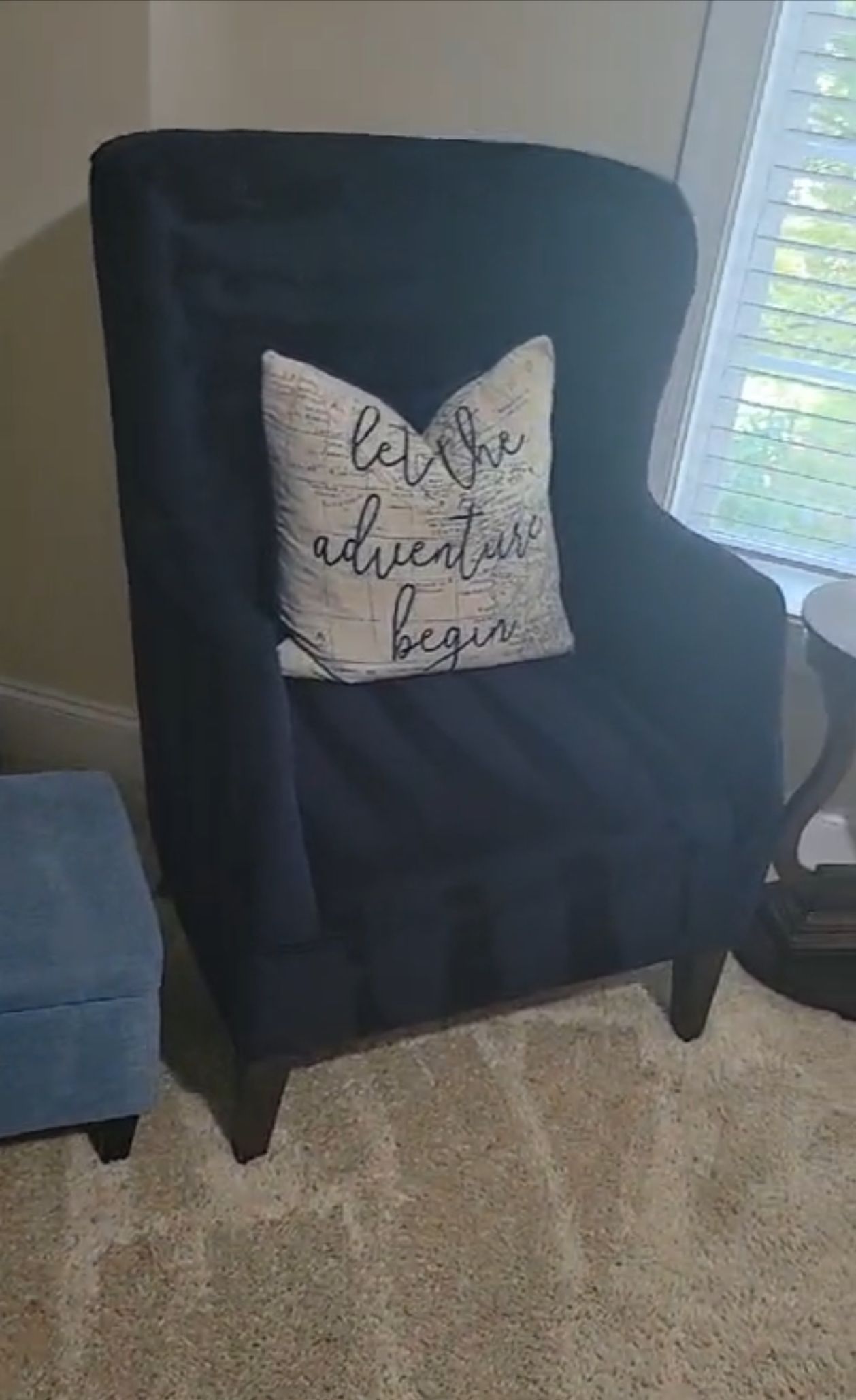 A black chair with a white pillow on it in a living room.