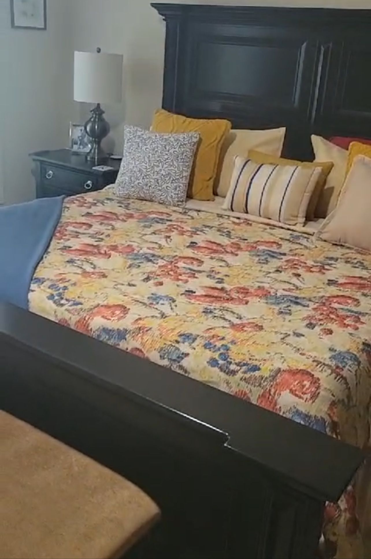 A bed with a floral comforter and pillows in a bedroom.