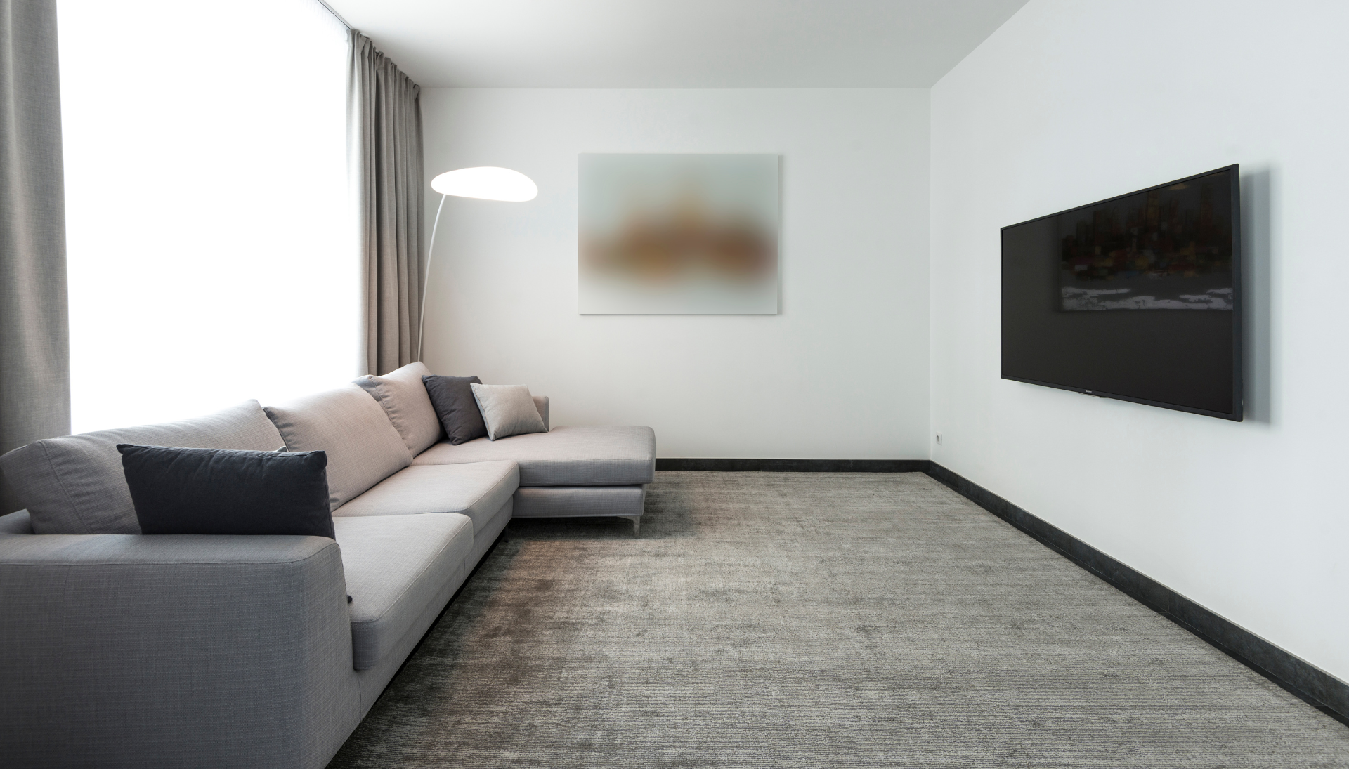 A living room with a couch and a flat screen tv on the wall.