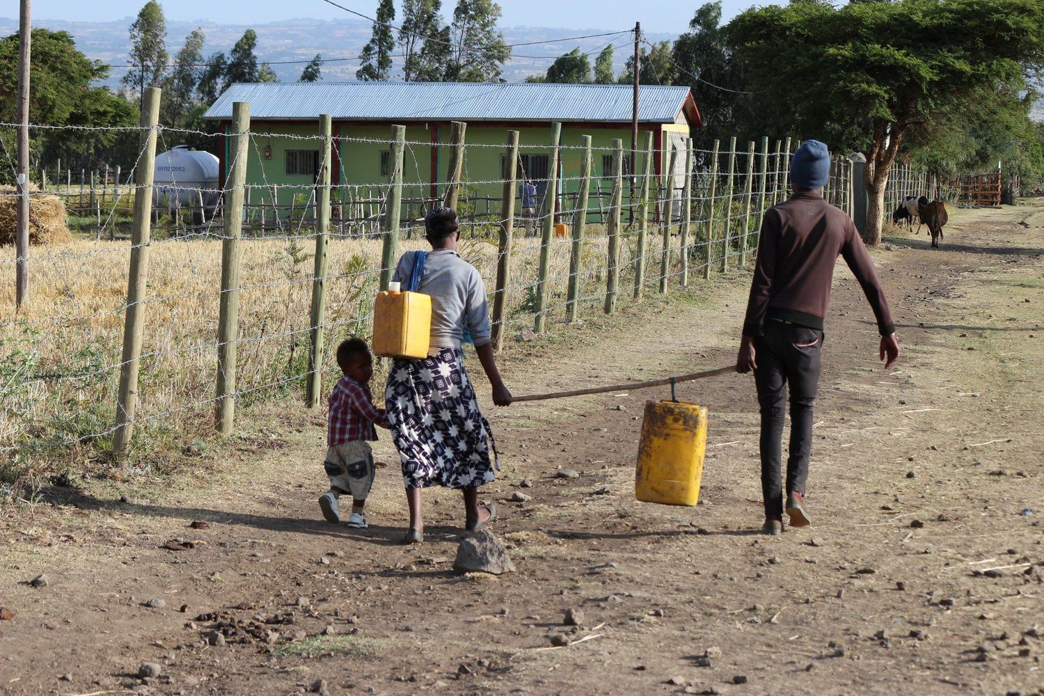 A group of people are walking down a dirt road