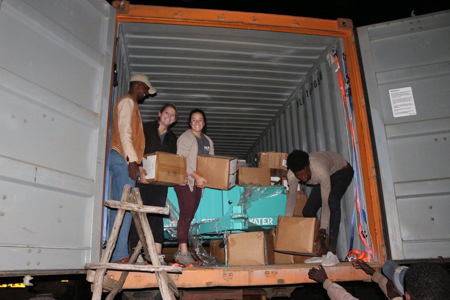 A group of people are loading boxes into a shipping container.