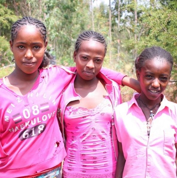 Three girls are posing for a picture and one of them is wearing a shirt that says 08-618