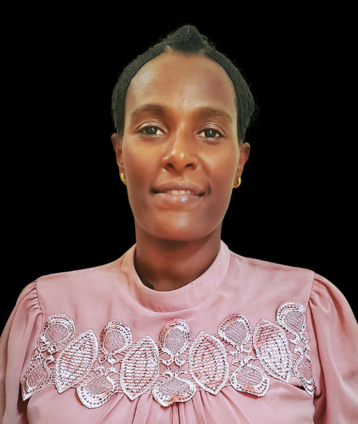 A woman wearing a tan jacket and a necklace is smiling for the camera.