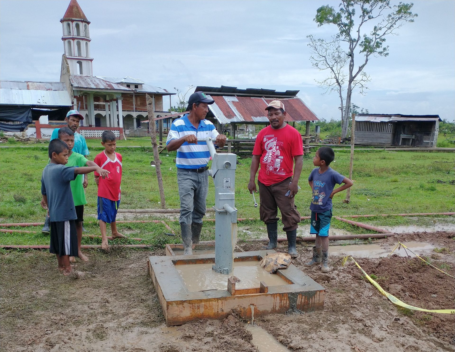 A group of men and boys are standing around a well