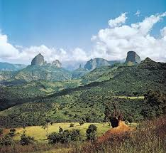 A view of a lush green valley with mountains in the background.