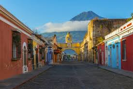 A row of colorful buildings on a cobblestone street with a mountain in the background.