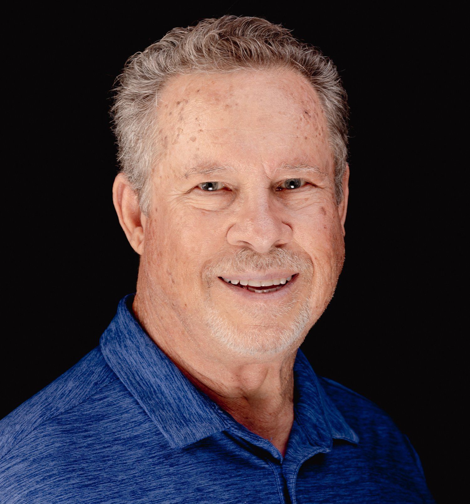 A man in a blue shirt is smiling for the camera.