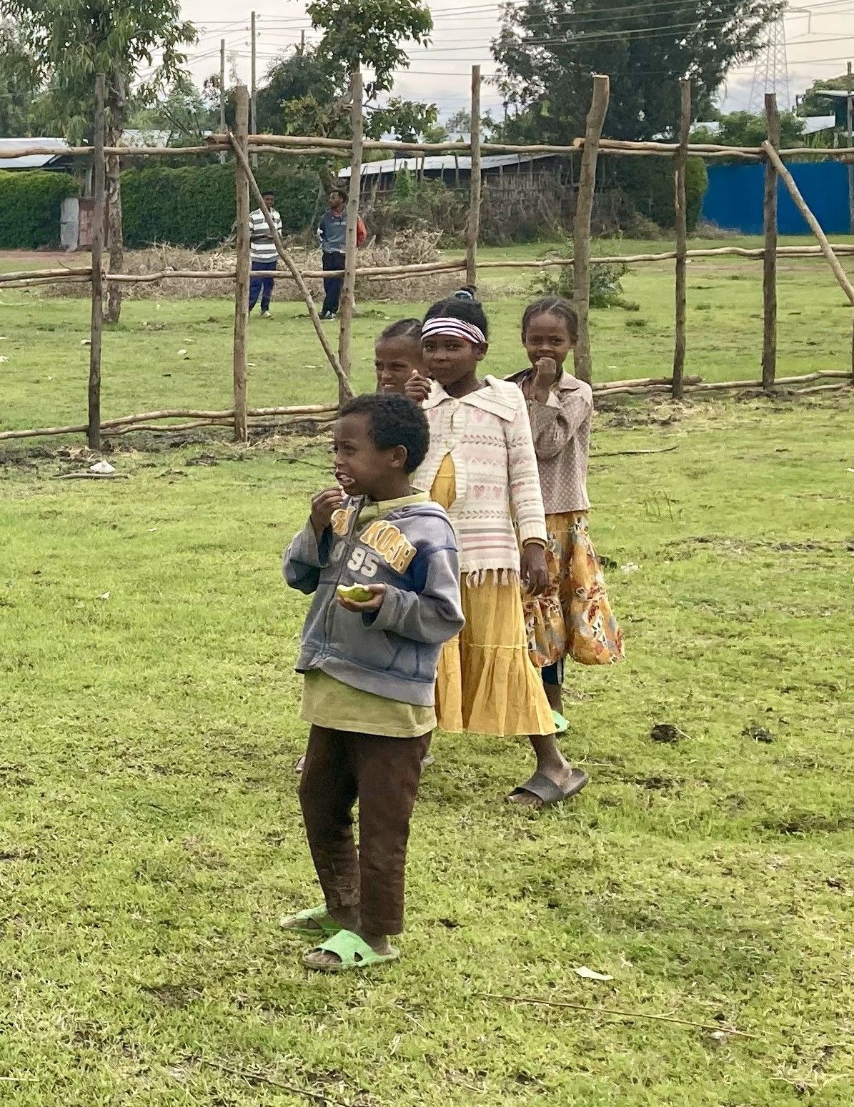 A group of children are standing in a grassy field.