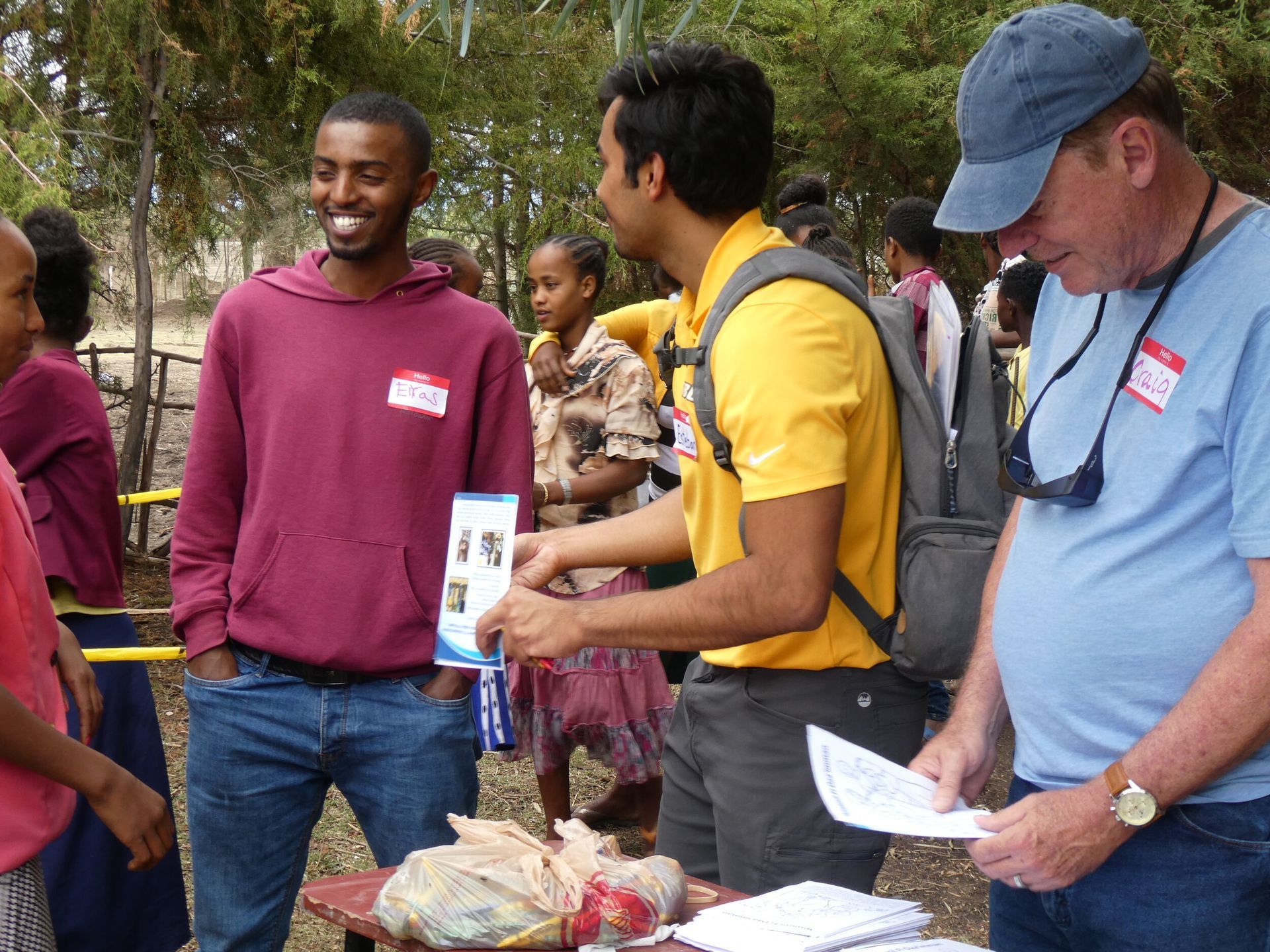 A man in a yellow shirt is talking to a group of people