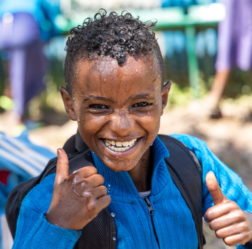 A young boy is smiling and giving a thumbs up