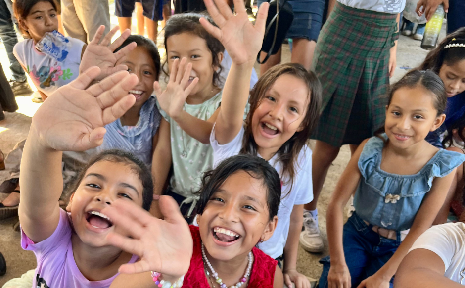 A group of girls are smiling and waving.