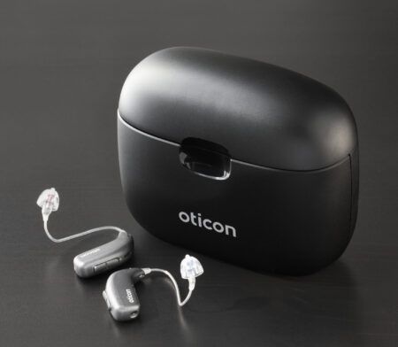 Svart hleðslutaska fyrir heyrnartæki frá Oticon með tveimur heyrnartækjum.