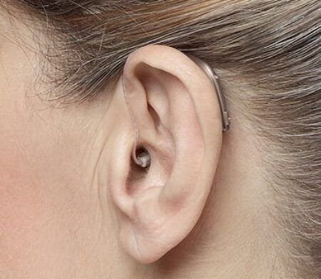 Nærmynd af eyra með heyrnartæki fyrir aftan eyrað og í eyrnagönginni.