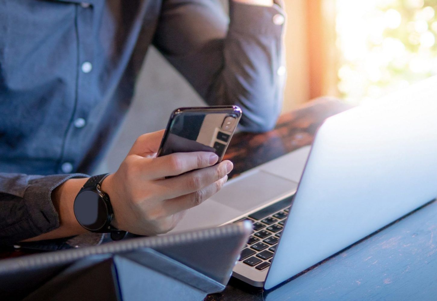 Maður heldur á snjallsíma, með fartölvu og spjaldtölvu, hugsanlega að vinna eða vinna í mörgum verkefnum samtímis.