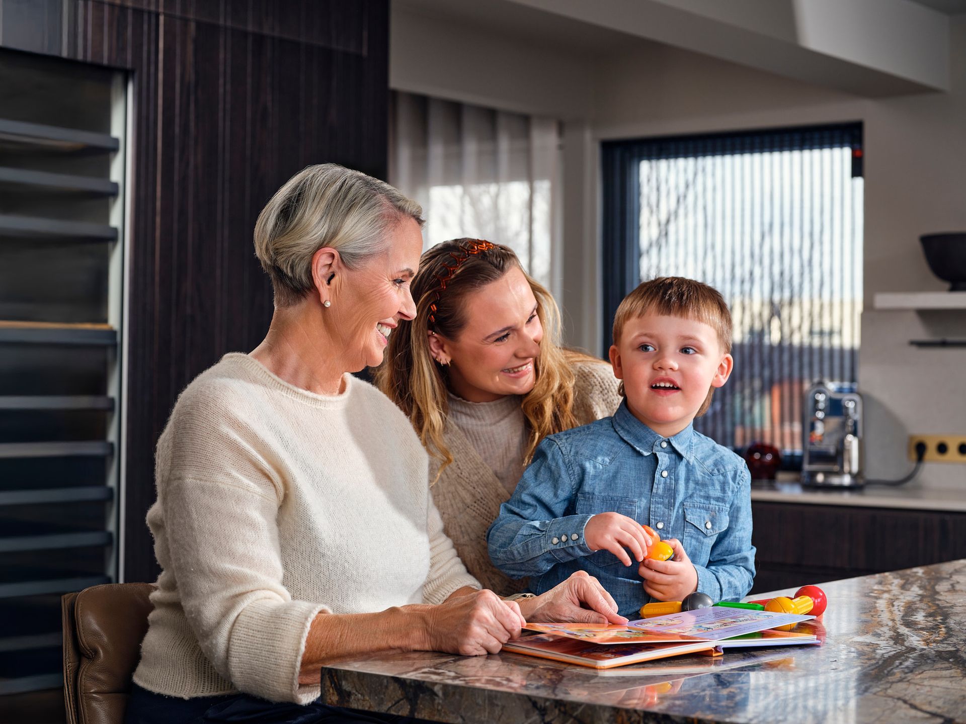 Kona faðmar eldri konu í sófa, báðar brosandi.