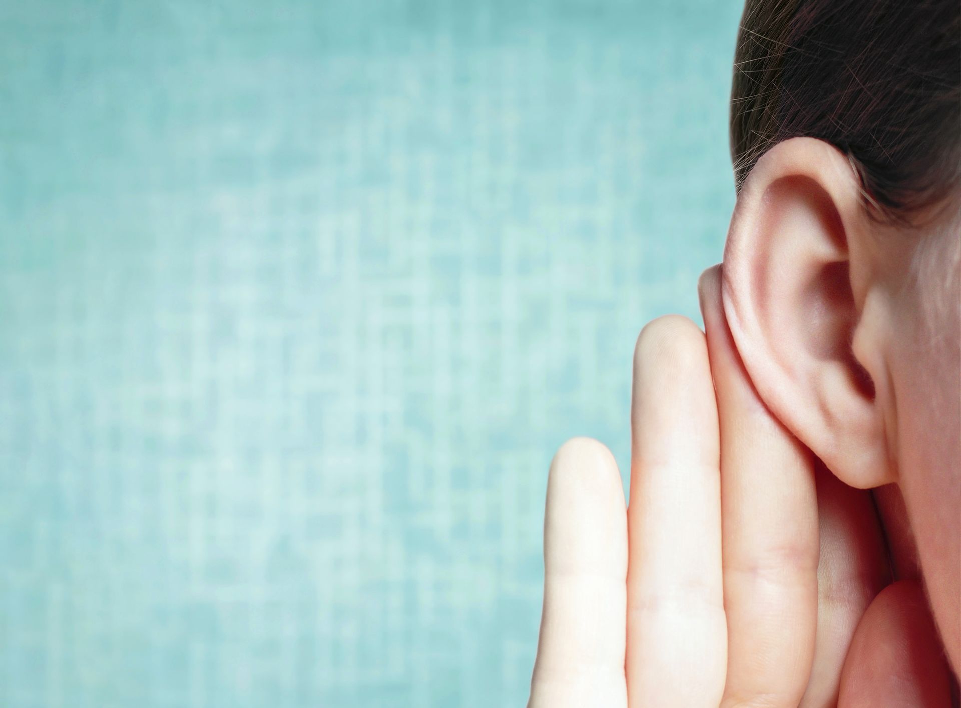 Eyra manns með hendinni utan um það, á ljósbláum bakgrunni, sem gefur til kynna hlustandi.