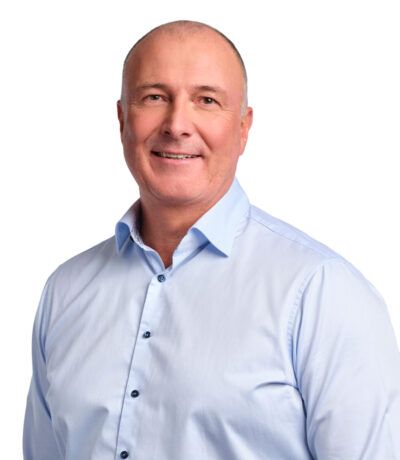 Brosandi maður í ljósbláum skyrtu, mynd af sér í stúdíó.