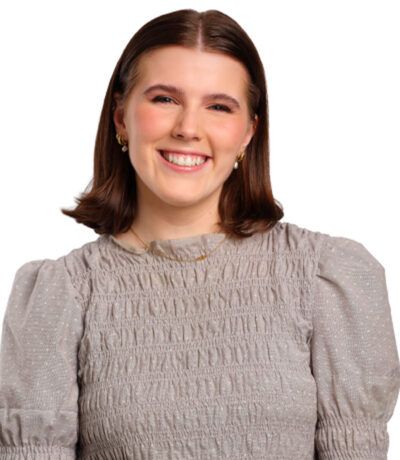 Brosandi kona, í gráum áferðarbol, litlum eyrnalokkum og stuttu brúnu hári.