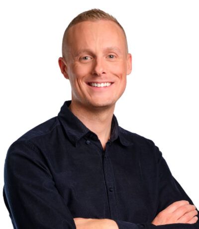 Maður með stutt, ljóst hár, brosandi, hendur krosslagðar, klæddur í dökkbláa skyrtu með hnappum.